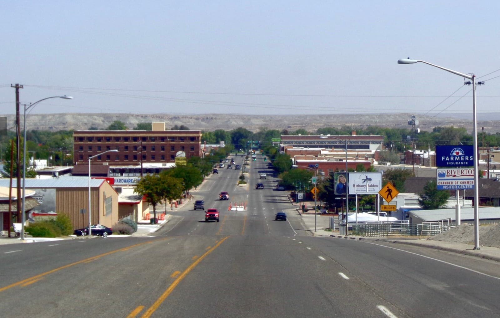 View down Riverton, Wyoming's main commercial corridor — downtown storefronts and wide streets with the open Wind River Basin and distant bluffs on the horizon