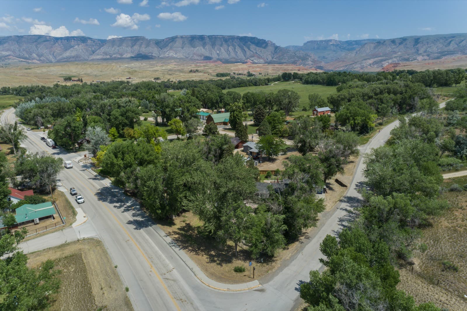 Aerial view of Shell, Wyoming — green meadows and cottonwoods at the foot of the red-rock cliffs of the Bighorn Mountain front